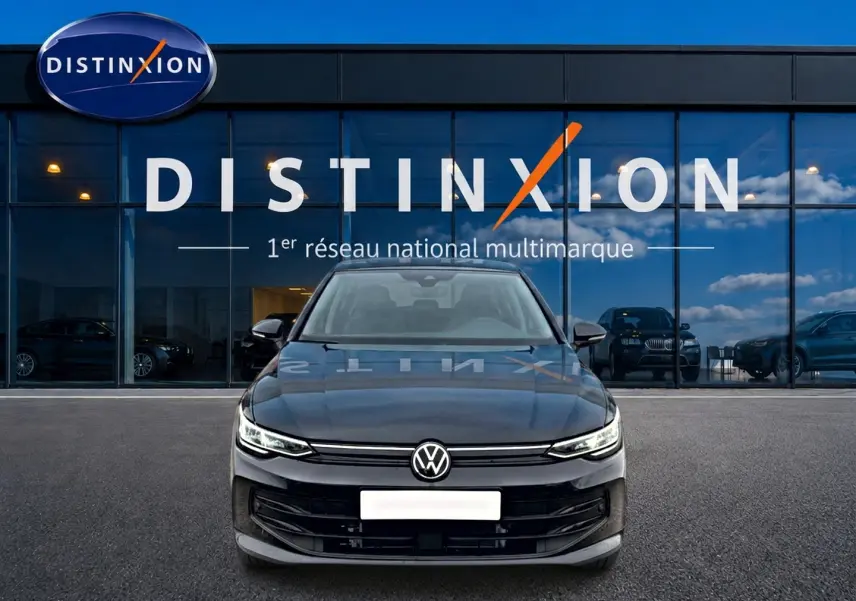 Volkswagen Golf 2026 noire vue de face, avec calandre épurée et phares LED allumés devant showroom Distinxion.