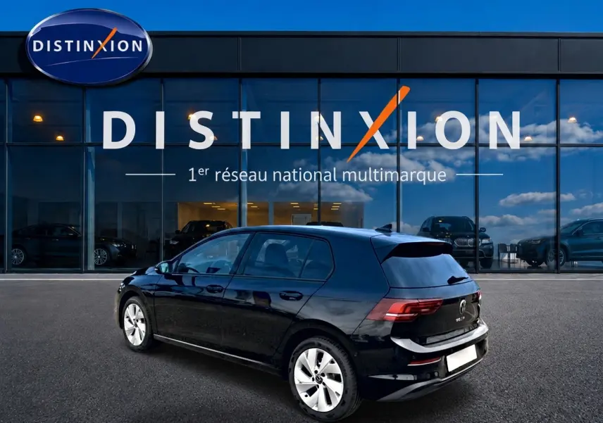 Volkswagen Golf noir vue 3/4 arrière droit, avec jantes alu 17 pouces, stationnée devant un showroom Distinxion.