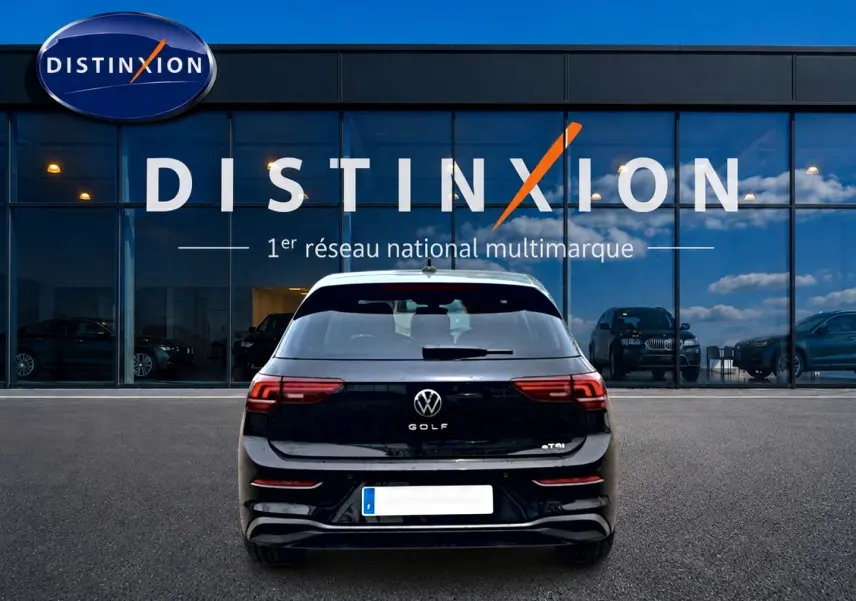 Vue arrière d'une Volkswagen Golf noire 2026 garée devant une vitrine avec enseigne Distinxion.