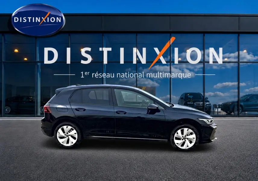 Profil côté gauche d'une Volkswagen Golf noire 2026 garée devant une vitrine avec logo Distinxion.
