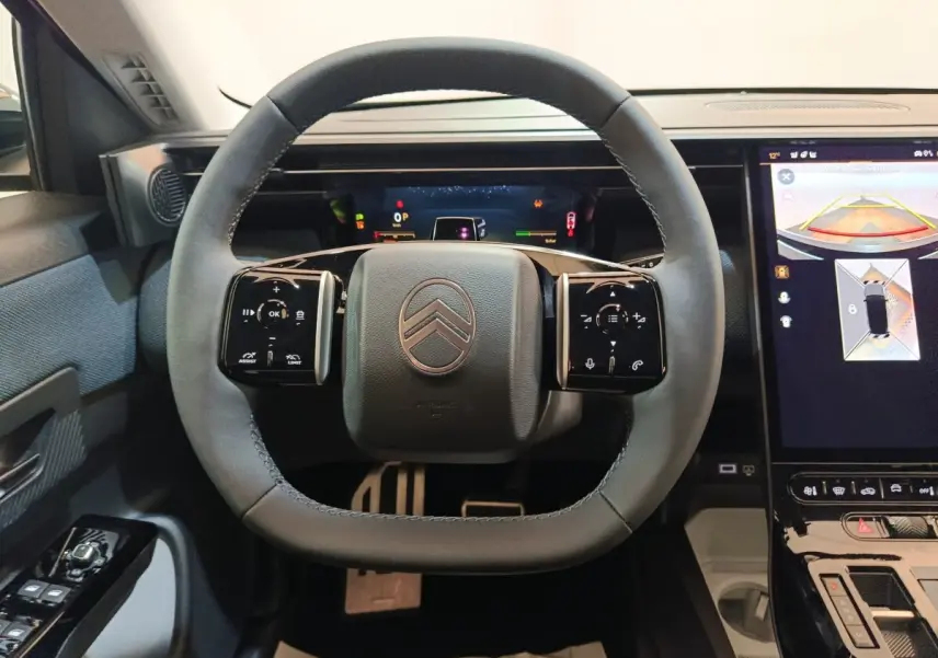 Vue rapprochée du volant cuir noir du Citroën C5 hybride 2026 avec tableau de bord digital et écran tactile de navigation.