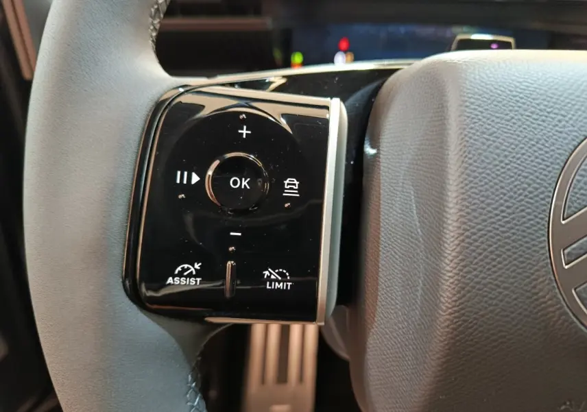Gros plan sur la commande multifonctions gauche du volant cuir noir du Citroën C5 Hybride 2026.