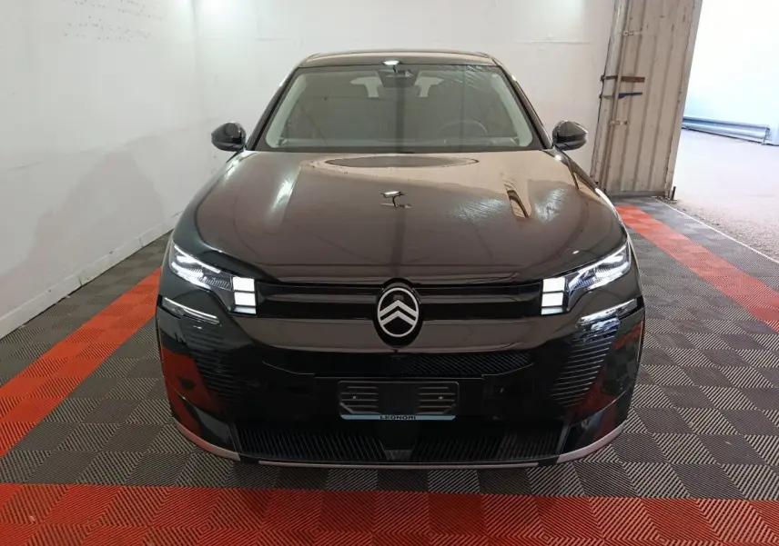 Vue frontale d'une Citroën C5 Hybride noire avec phares LED allumés dans un garage.