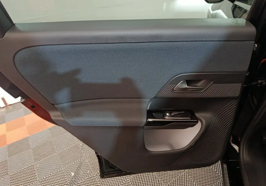 Intérieur côté gauche de la porte arrière noire d'une Citroën C5 Hybride 2026 avec insert texturé et poignée argentée.
