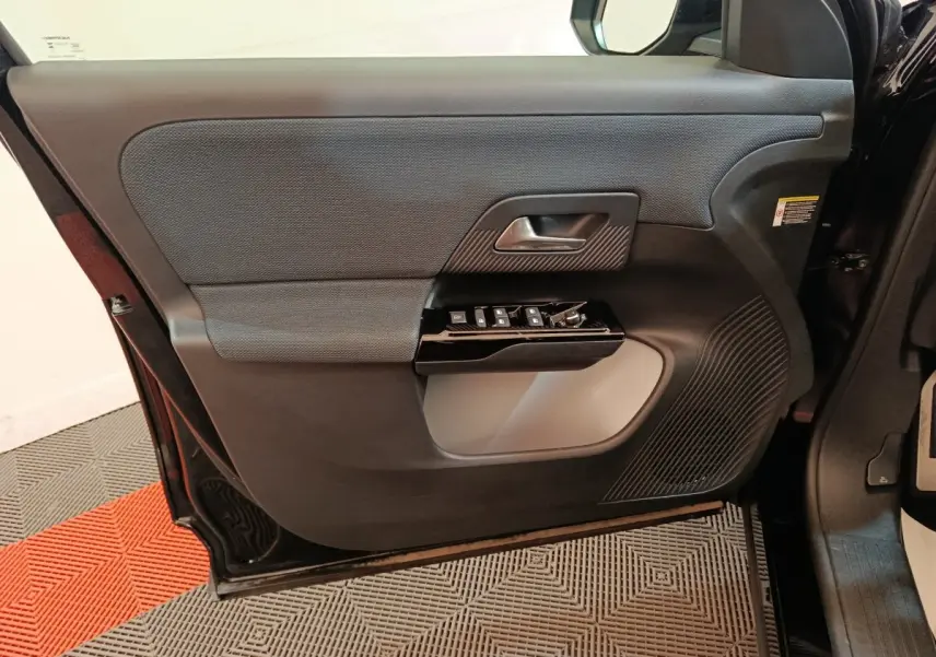 Vue intérieure de la porte avant gauche noire du Citroën C5 Hybride 2026 avec commandes de vitres et poignée intégrée.