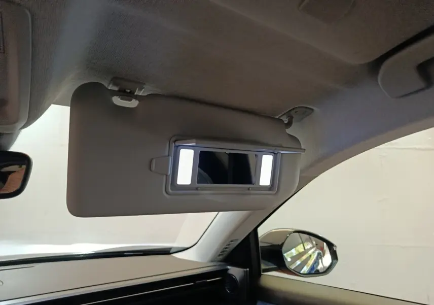 Intérieur de la Citroën C5 Hybride noir, vue côté passager avec pare-soleil et miroir éclairé déployé.