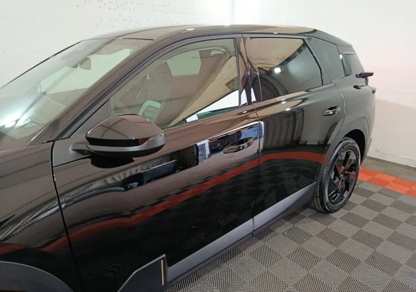Vue latérale côté gauche d'une Citroën C5 Hybride noire avec jantes noires et détails de carrosserie modernes.