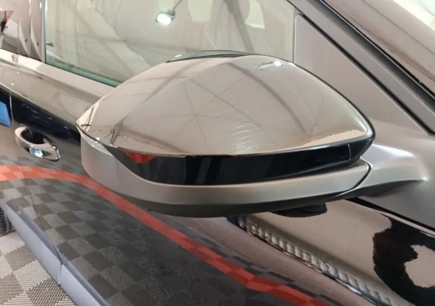 Gros plan sur le rétroviseur côté gauche noir brillant d'une Citroën C5 hybride 2026 avec portière noire en arrière-plan.