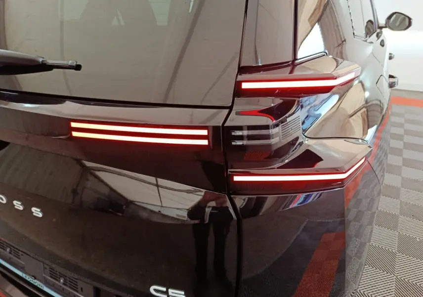 Vue arrière droite du Citroën C5 hybride noir, mettant en valeur ses feux arrière LED horizontaux distinctifs.