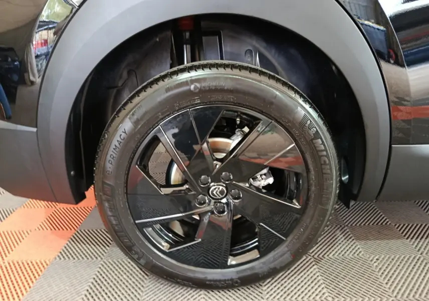 Gros plan sur la roue avant gauche noire avec jante en alliage noir brillant du Citroën C5 Hybride 2026.