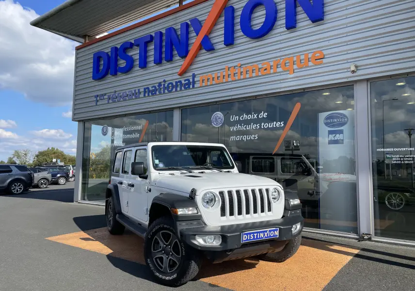 Jeep Wrangler blanc vu de face à 3/4 gauche, avec calandre à sept fentes et jantes noires distinctives.