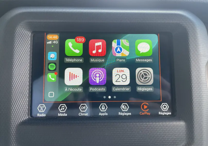 Écran tactile central du Jeep Wrangler 2018 blanc affichant Apple CarPlay et plusieurs applications connectées.