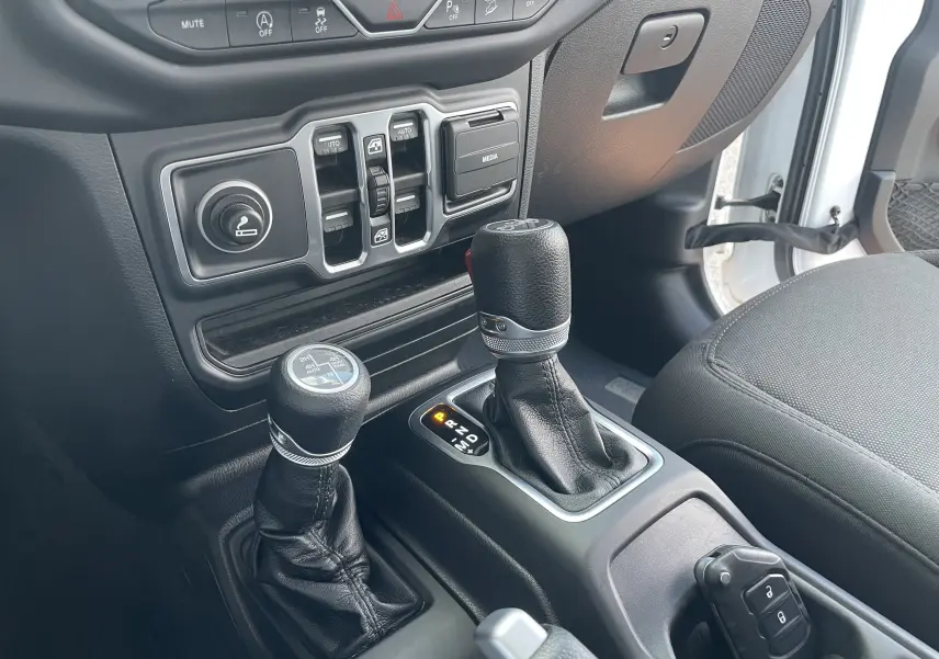 Vue intérieure côté passager du levier de vitesses automatique et du levier de transfert sur Jeep Wrangler blanc 2018.