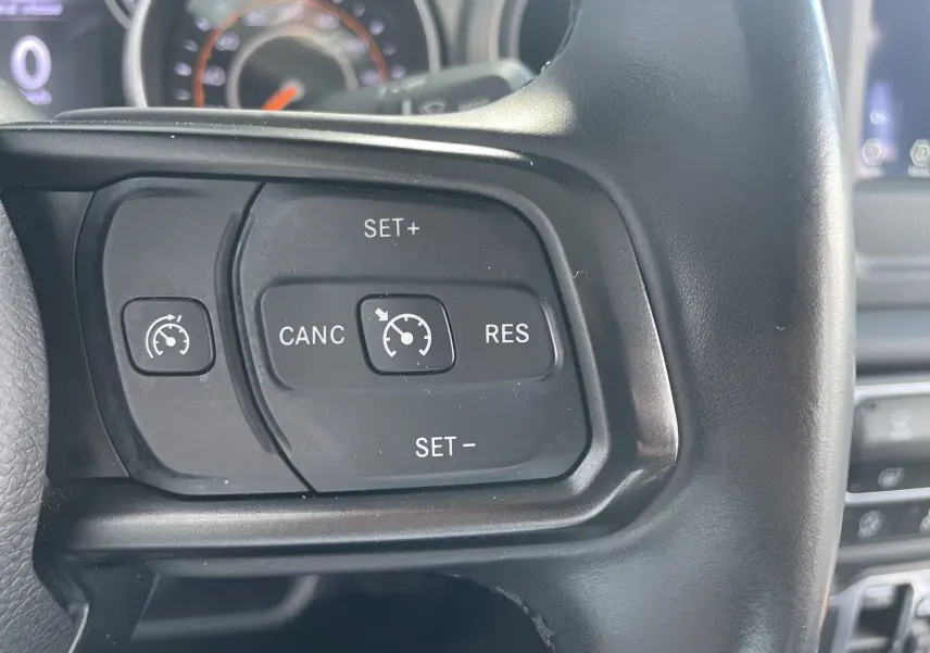 Gros plan sur les commandes de régulateur de vitesse au volant noir du Jeep Wrangler blanc 2018.