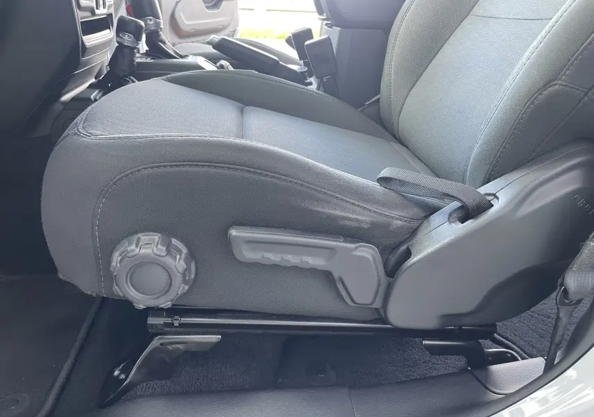 Gros plan sur le siège avant droit en tissu gris noir du Jeep Wrangler blanc 2018, montrant les réglages manuels.