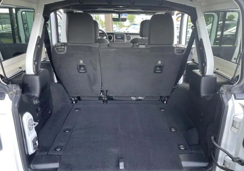 Coffre ouvert du Jeep Wrangler blanc 2018, vue depuis l'arrière montrant banquette arrière et espace de chargement spacieux.