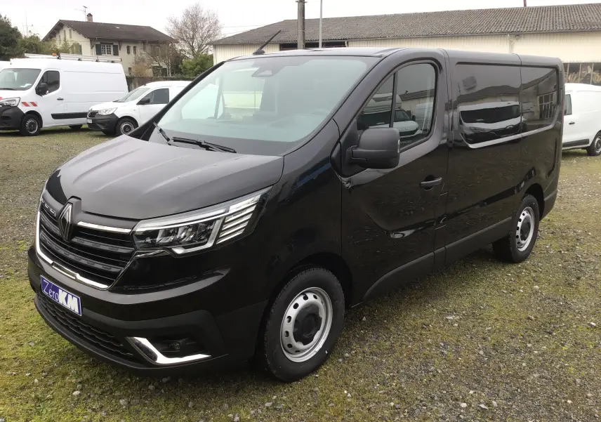 Vue 3/4 avant droite d’un Renault Trafic Fourgon noir 2025 avec calandre chromée et jantes acier.