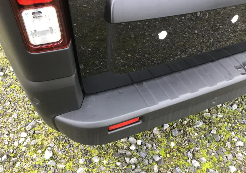 Gros plan sur le coin arrière gauche du Renault Trafic Fourgon noir, mettant en valeur le feu arrière et le pare-chocs.