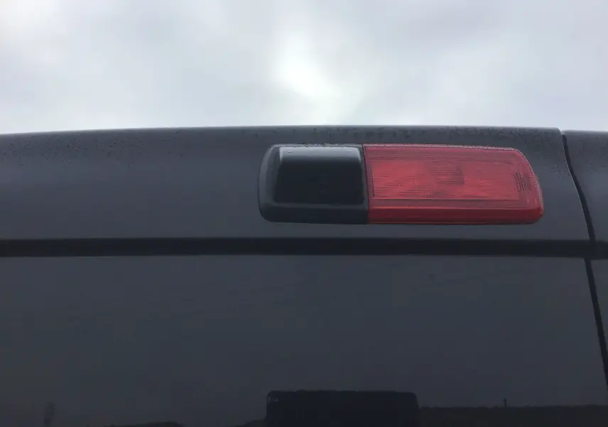 Gros plan sur la caméra de recul intégrée au feu stop arrière du Renault Trafic Fourgon noir, version 2025.