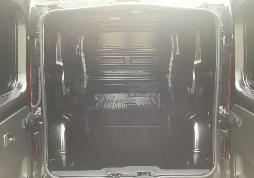Vue arrière du fourgon Renault Trafic L1H1 noir, montrant l’espace de chargement vide et les portes ouvertes.
