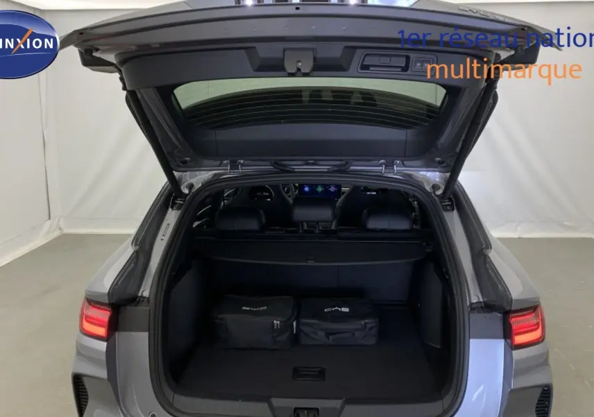 Vue arrière du coffre ouvert du BYD SEAL U Time Grey 2025 avec feux arrière LED allumés et deux sacs de rangement à l’intérieur.