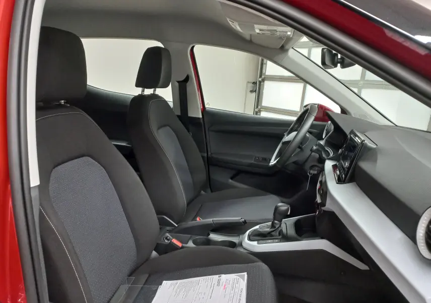 Vue intérieure côté conducteur du SEAT Arona rouge Désir avec toit noir, montrant les sièges et la console centrale.