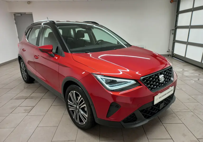 SEAT Arona rouge Désir avec toit noir Minuit, vue 3/4 avant droit en intérieur, jantes alliage distinctives.