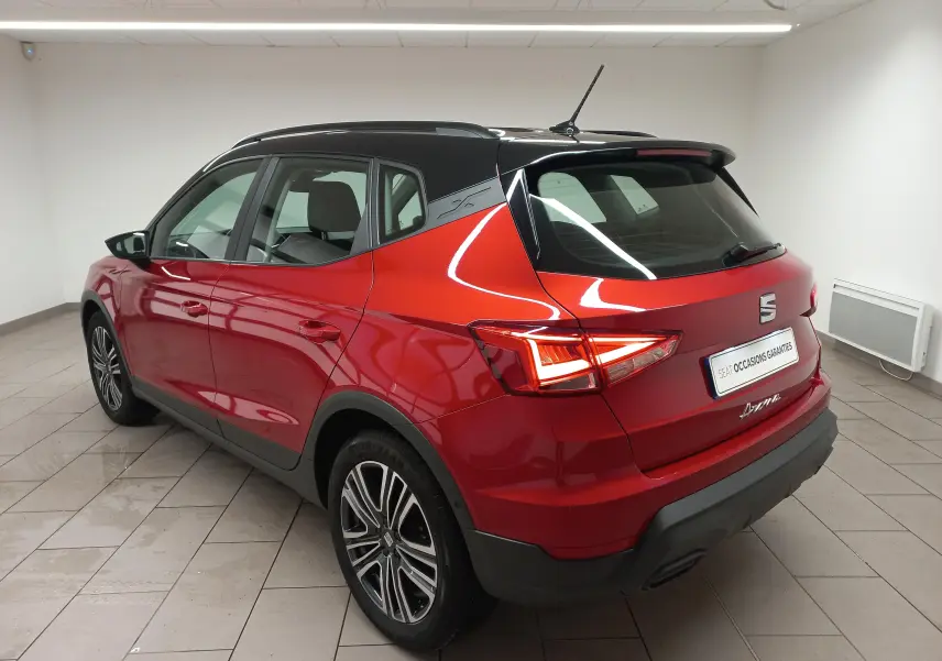 Vue 3/4 arrière droite du SEAT Arona rouge Désir avec toit noir Minuit, soulignant ses feux arrière LED et jantes alliage.