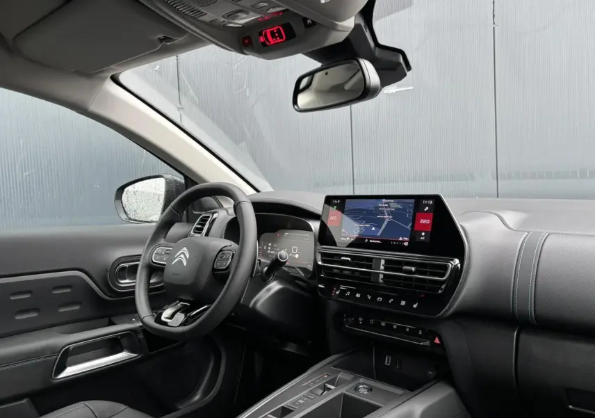 Intérieur avant droit du Citroën C5 Aircross 2025, tableau de bord noir avec écran tactile et volant multifonctions.