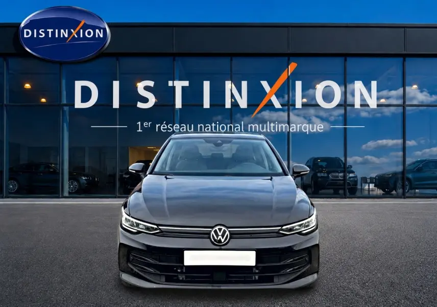 Vue frontale d'une Volkswagen Golf noire 2026 garée devant une vitrine avec logo Distinxion en arrière-plan.