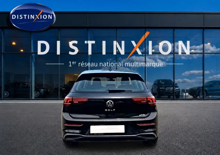 Vue arrière d'une Volkswagen Golf noire 2026 garée devant une vitrine avec logo Distinxion.