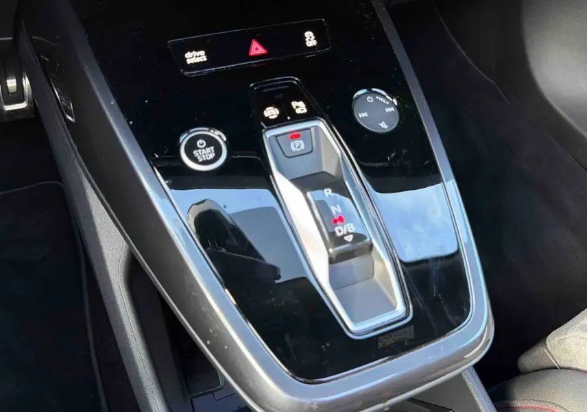 Gros plan sur la console centrale noire brillante de l'Audi Q4 e-tron 45 avec levier de vitesses automatique et boutons fonctionnels.