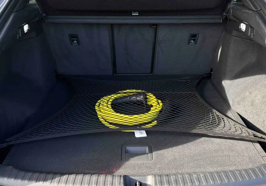 Coffre ouvert de l'Audi Q4 e-tron gris galet avec câble de recharge jaune maintenu par un filet noir.