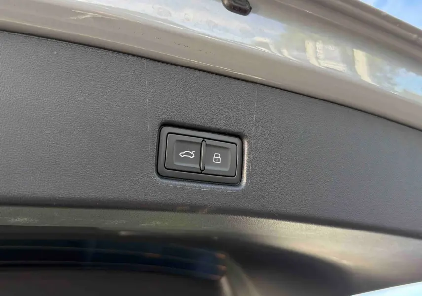Gros plan sur les boutons d'ouverture et de verrouillage du hayon électrique du coffre d'un Audi Q4 e-tron gris galet.
