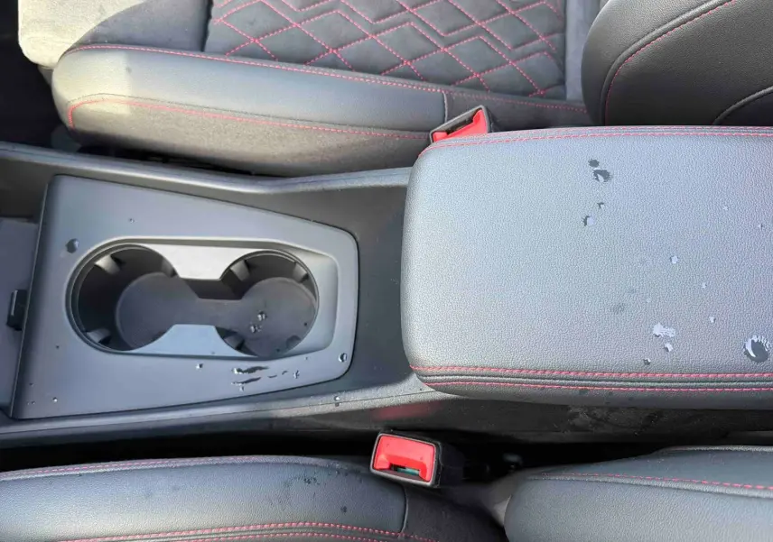 Vue rapprochée de la console centrale et accoudoir gris avec surpiqûres rouges de l'Audi Q4 e-tron 2025.