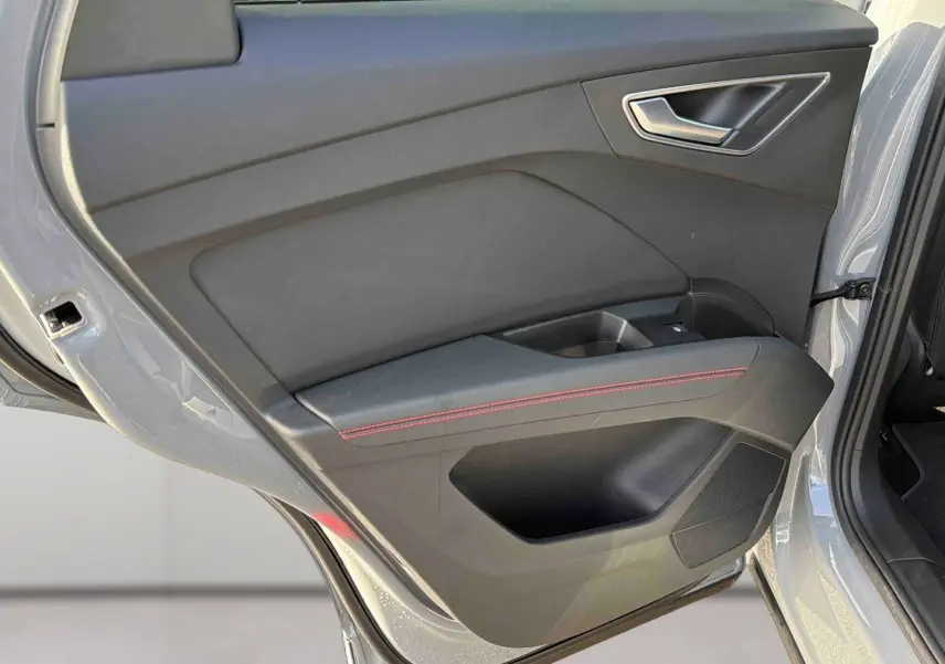 Vue intérieure de la porte arrière gauche gris galet de l'Audi Q4 e-tron avec surpiqûres rouges et poignée argentée.