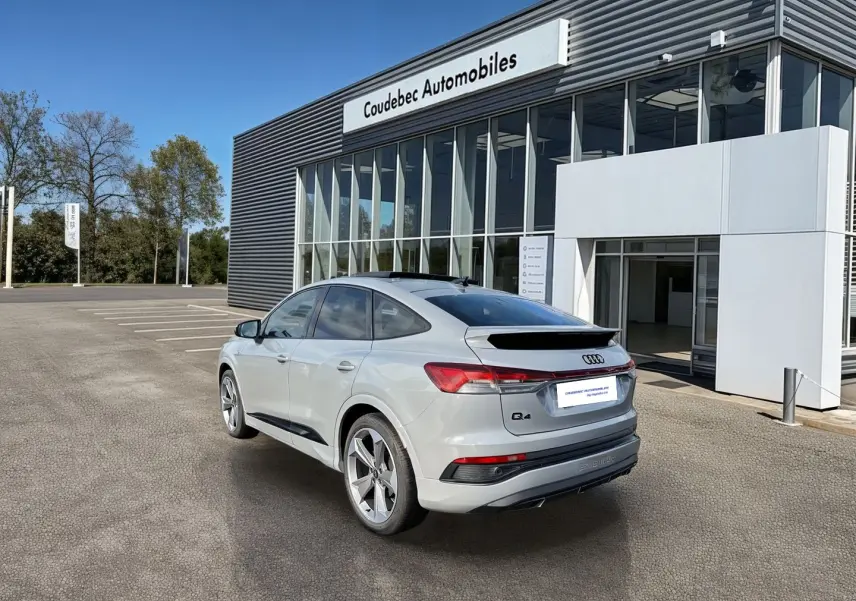 Audi Q4 e-tron gris galet vue 3/4 arrière droit, avec jantes 19 pouces et toit panoramique noir.