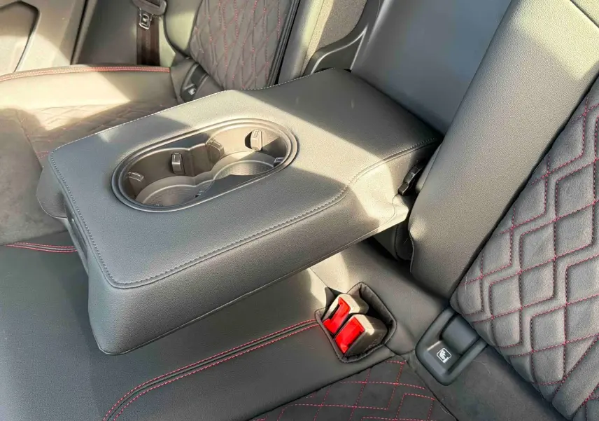 Gros plan sur l'accoudoir central arrière avec porte-gobelets et sellerie tissu noir à surpiqûres rouges de l'Audi Q4 e-tron.