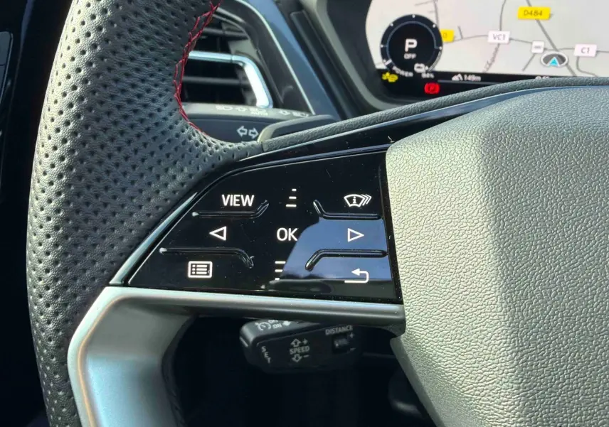 Gros plan sur le volant cuir perforé avec commandes tactiles à gauche et affichage numérique du tableau de bord de l’Audi Q4 e-tron gris galet.