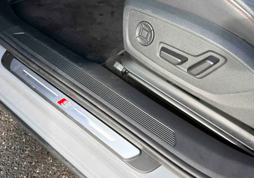 Gros plan sur la plaque de seuil de porte avec logo S et siège avant en cuir noir sur Audi Q4 e-tron gris galet.
