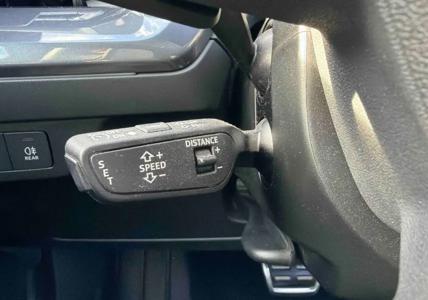 Gros plan sur la commande de régulateur de vitesse au volant d’un Audi Q4 e-tron gris galet 2025.