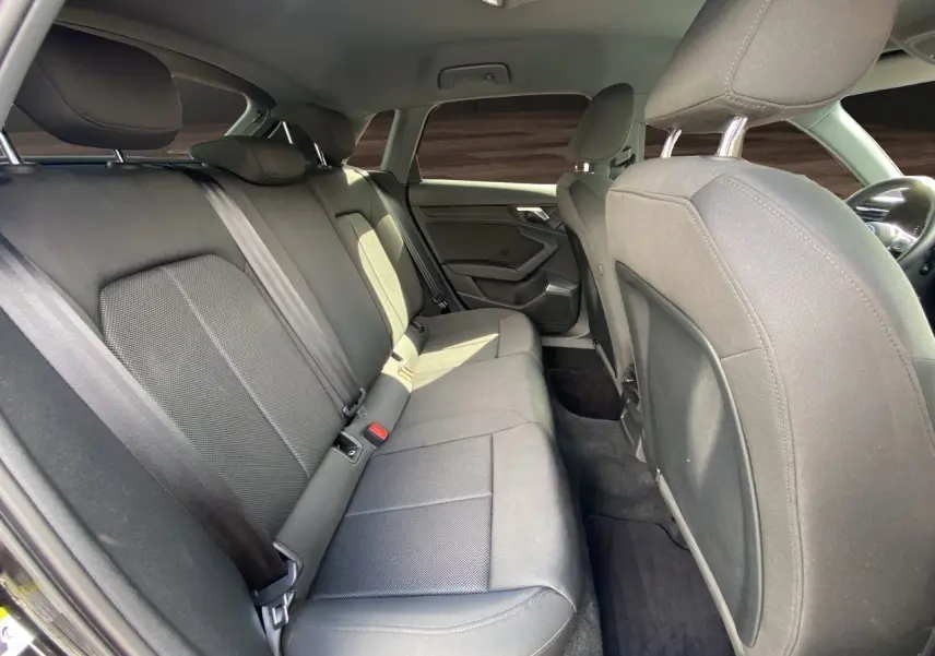 Vue intérieure côté arrière droit de l'Audi A3 Sportback 2021 avec sièges arrière en tissu noir et ceintures de sécurité.