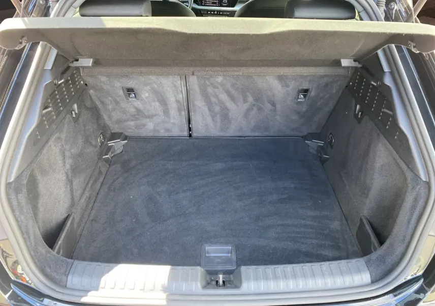 Coffre ouvert vu de l'arrière d'une Audi A3 Sportback noire, montrant un espace de chargement propre et spacieux.