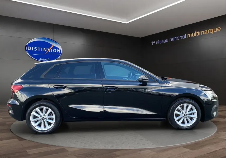 Profil côté gauche d'une Audi A3 Sportback noire 2021, avec jantes argentées et vitres teintées en showroom.