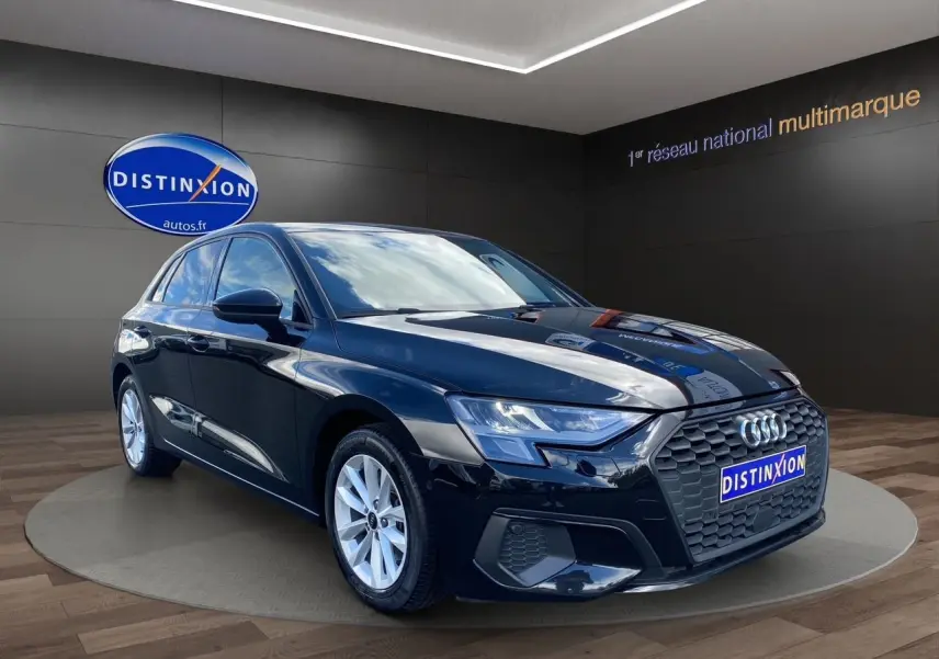 Audi A3 Sportback noire vue 3/4 avant droit, avec calandre hexagonale et jantes argentées en showroom