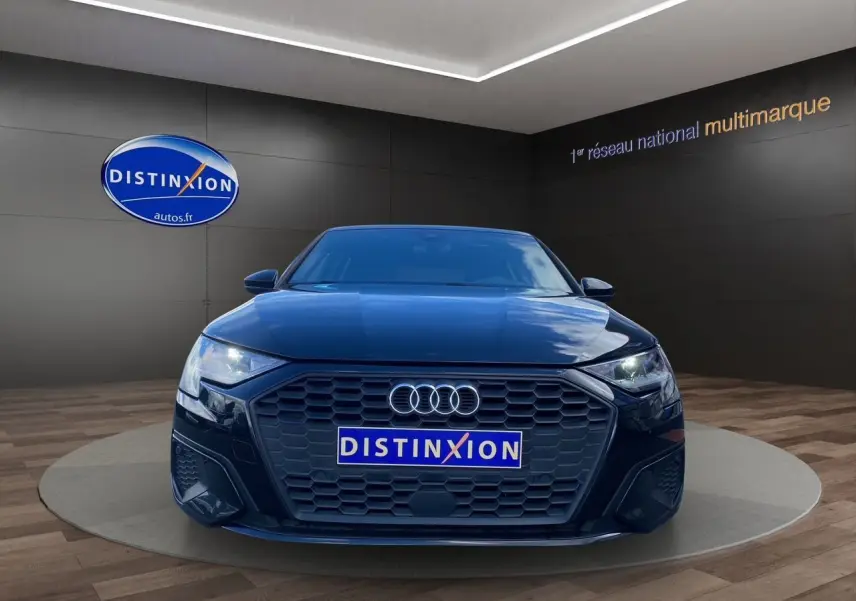 Vue frontale d'une Audi A3 Sportback noire 2021 avec calandre hexagonale et phares LED allumés.