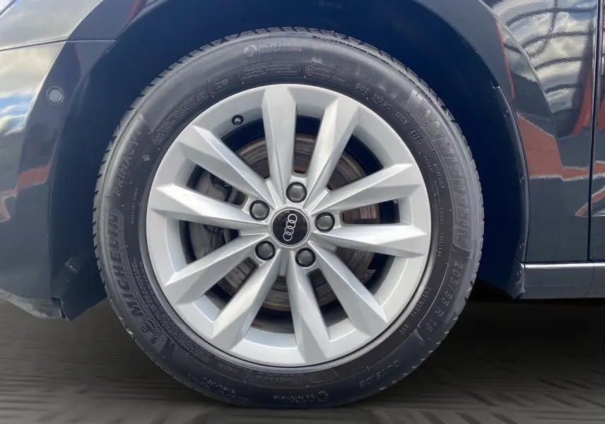 Gros plan sur la roue avant droite de l'Audi A3 Sportback noire, mettant en valeur la jante en alliage et le pneu Michelin.