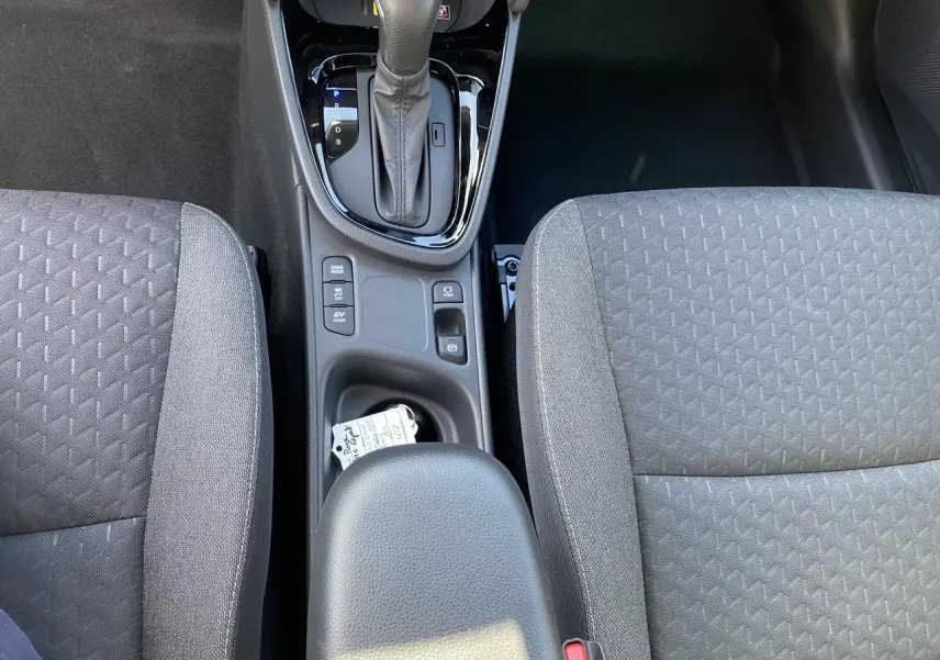 Vue plongeante sur la console centrale et les sièges gris en tissu du Toyota Yaris Cross hybride 2025.
