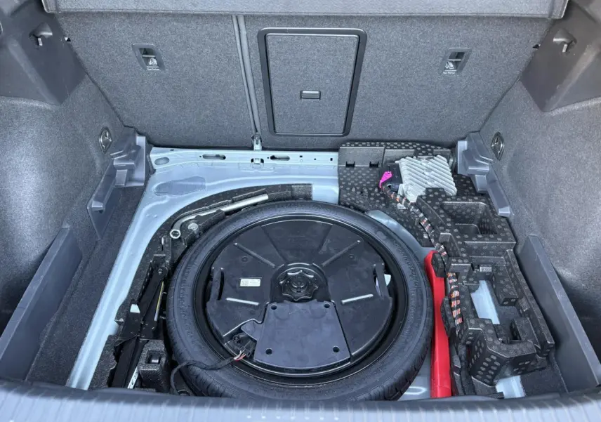Vue plongeante sur la roue de secours compacte et le rangement gris du coffre du CUPRA Formentor 2024.