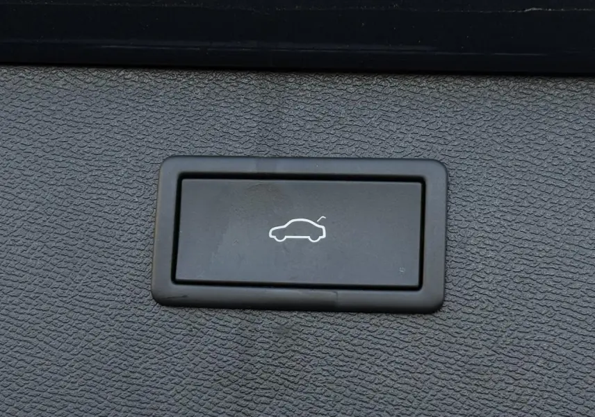 Bouton noir de hayon électrique avec pictogramme blanc, sur fond texturé gris foncé à l'intérieur du CUPRA Formentor.